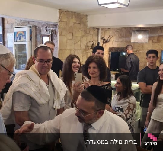 איש בחלוק לבן עם כיפה, מוקף אנשים